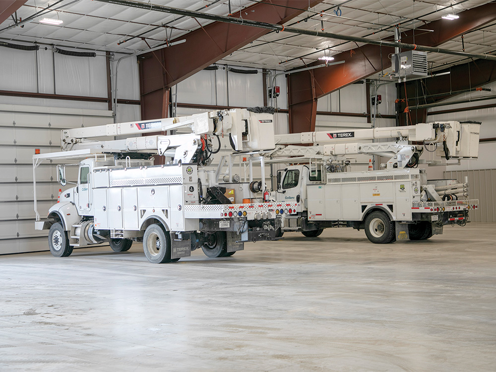 CoServ bucket trucks are stored in a climate-controlled garage with automatic doors.