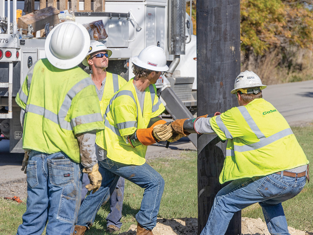 Crew Supervisor Cramer Basham watches linemen (from left to right) Waylon Wilson, Noah Luna, and Mason Horton
secure a new utility pole in place.