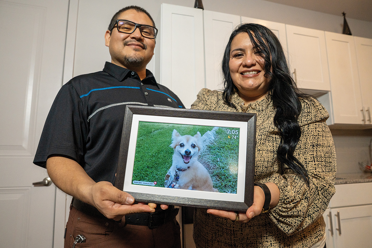 Ricardo Pena and Denys Lopez with a photo of their late dog Nikki, who passed after an illness. CoServ helped Ricard and Denys with a payment plan during their difficult time.